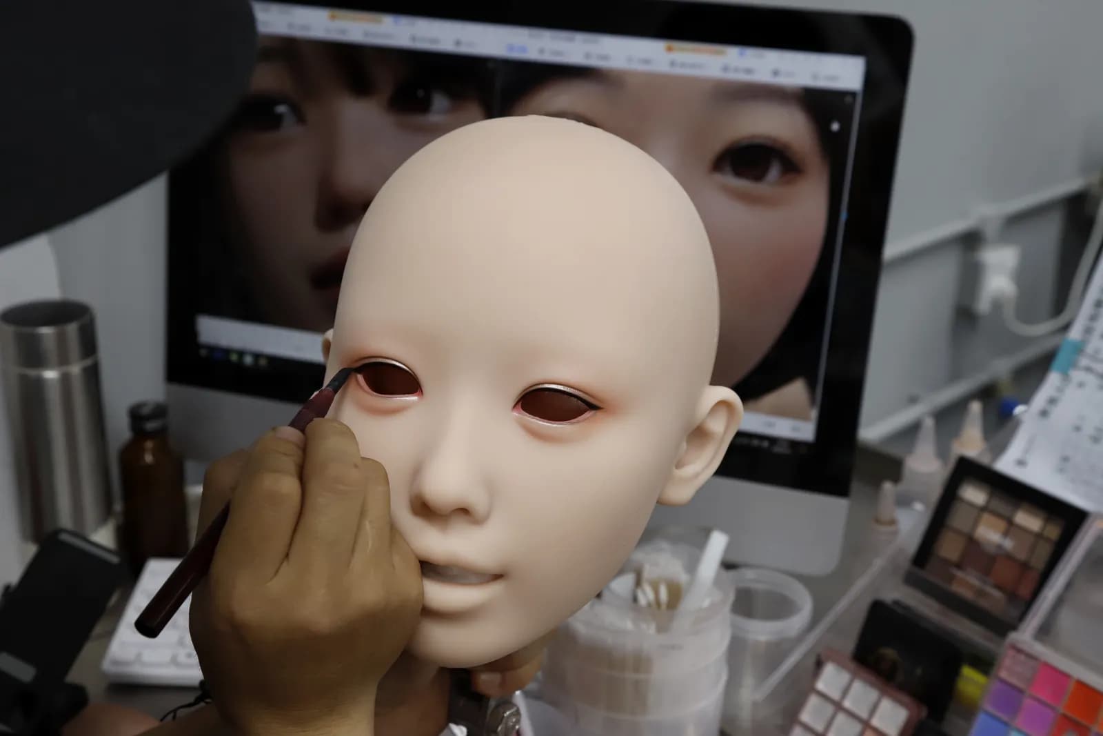 An artisan hand-painting the eye detail on a doll face